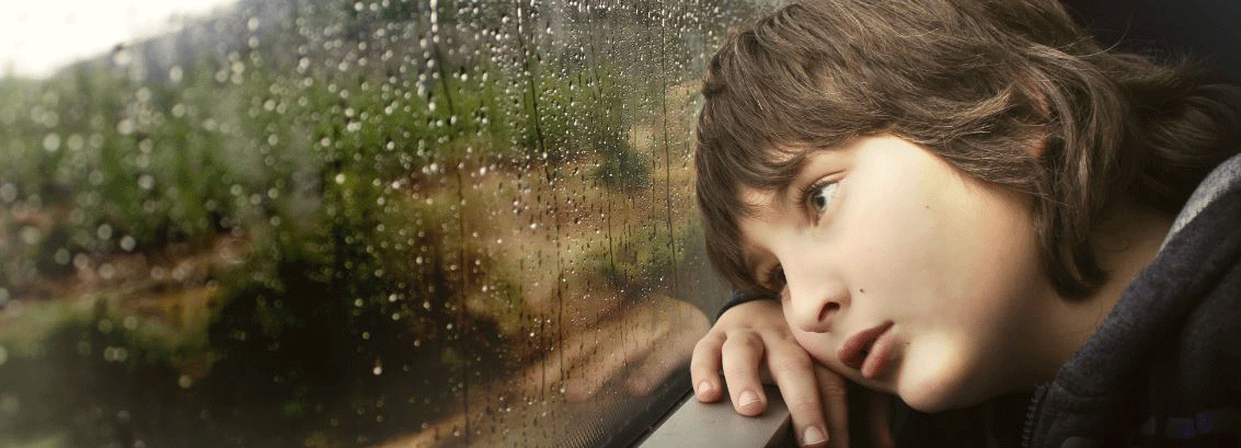 Pojke ser ut genom tågfönster